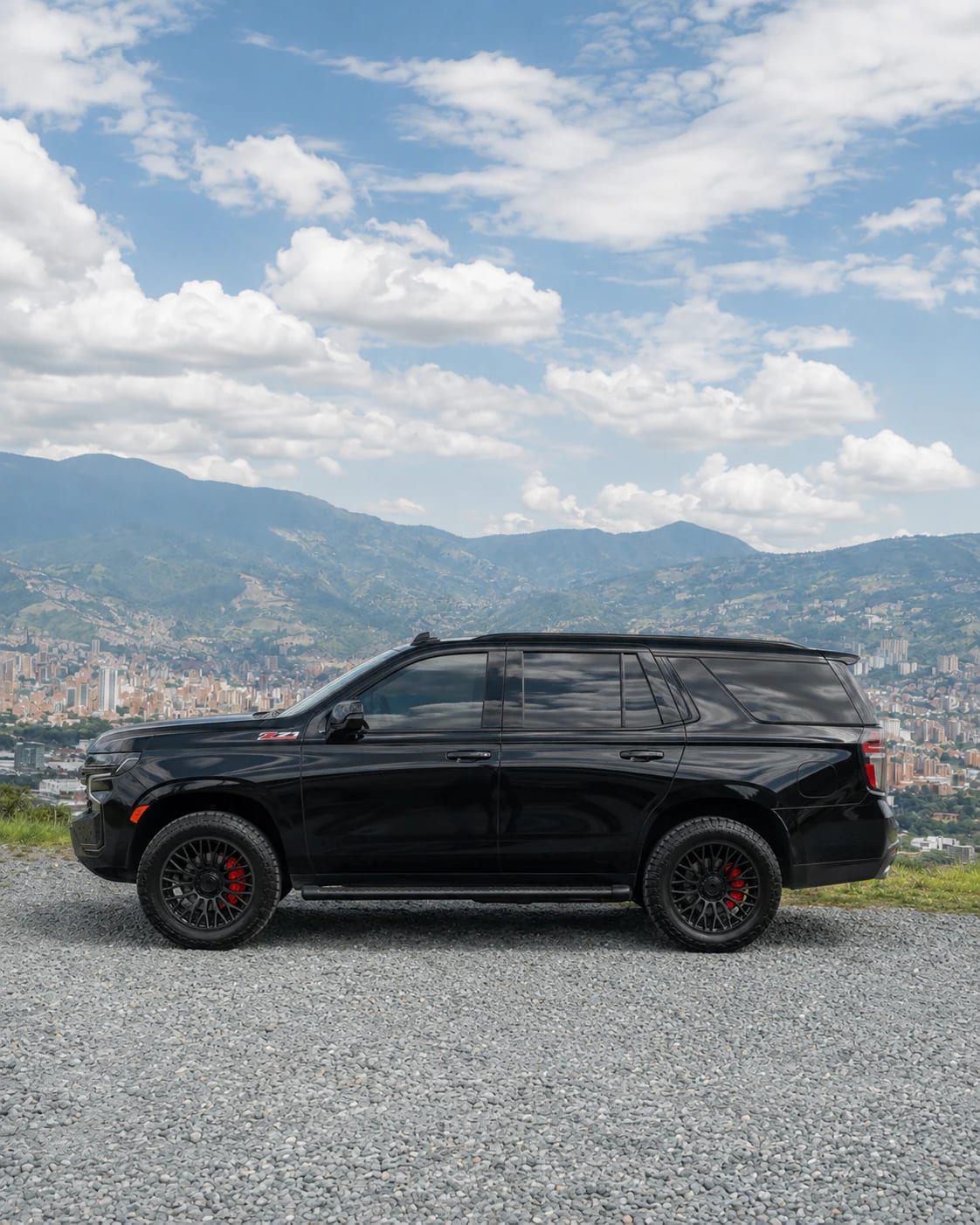 Perfil completo de la Chevrolet Tahoe negra sobre grava, con la cordillera detrás.