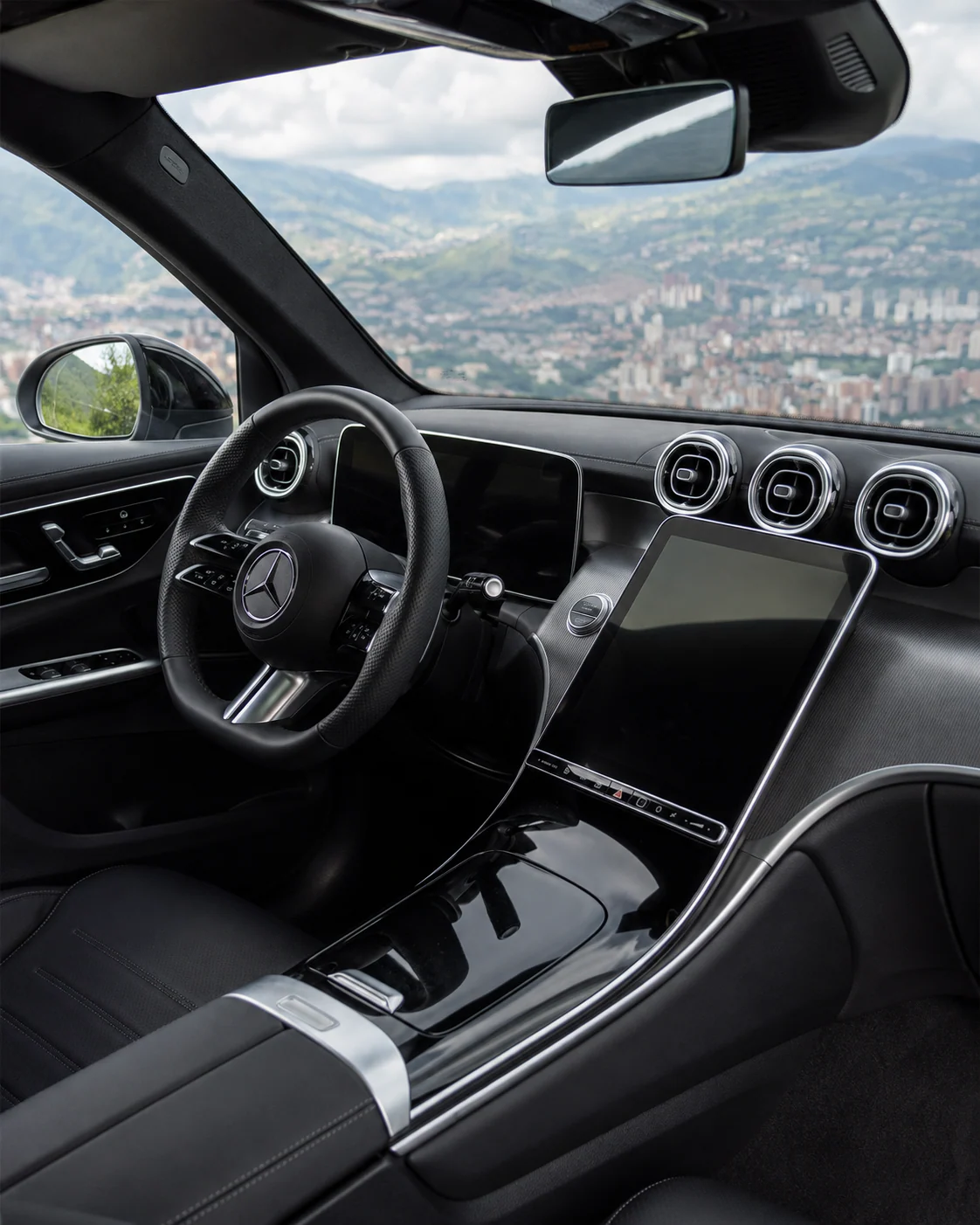 Puesto de conducción de la Mercedes-Benz GLC 300: volante de radios planos, pantalla central inclinada y consola.