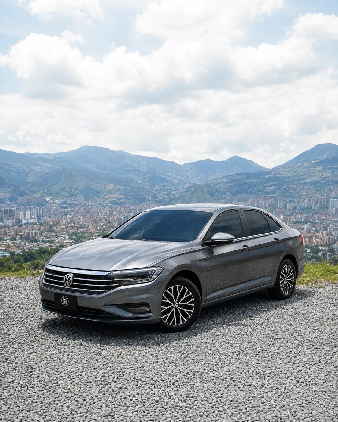 Grey Volkswagen Jetta, front three-quarter view, at a lookout with Medellín behind.